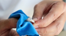 person holding ring while using microfiber cloth to clean it