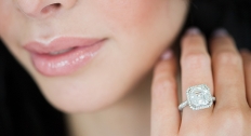 woman shows off square engagement ring close to face