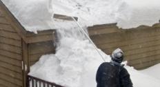 man clearing snow from roof